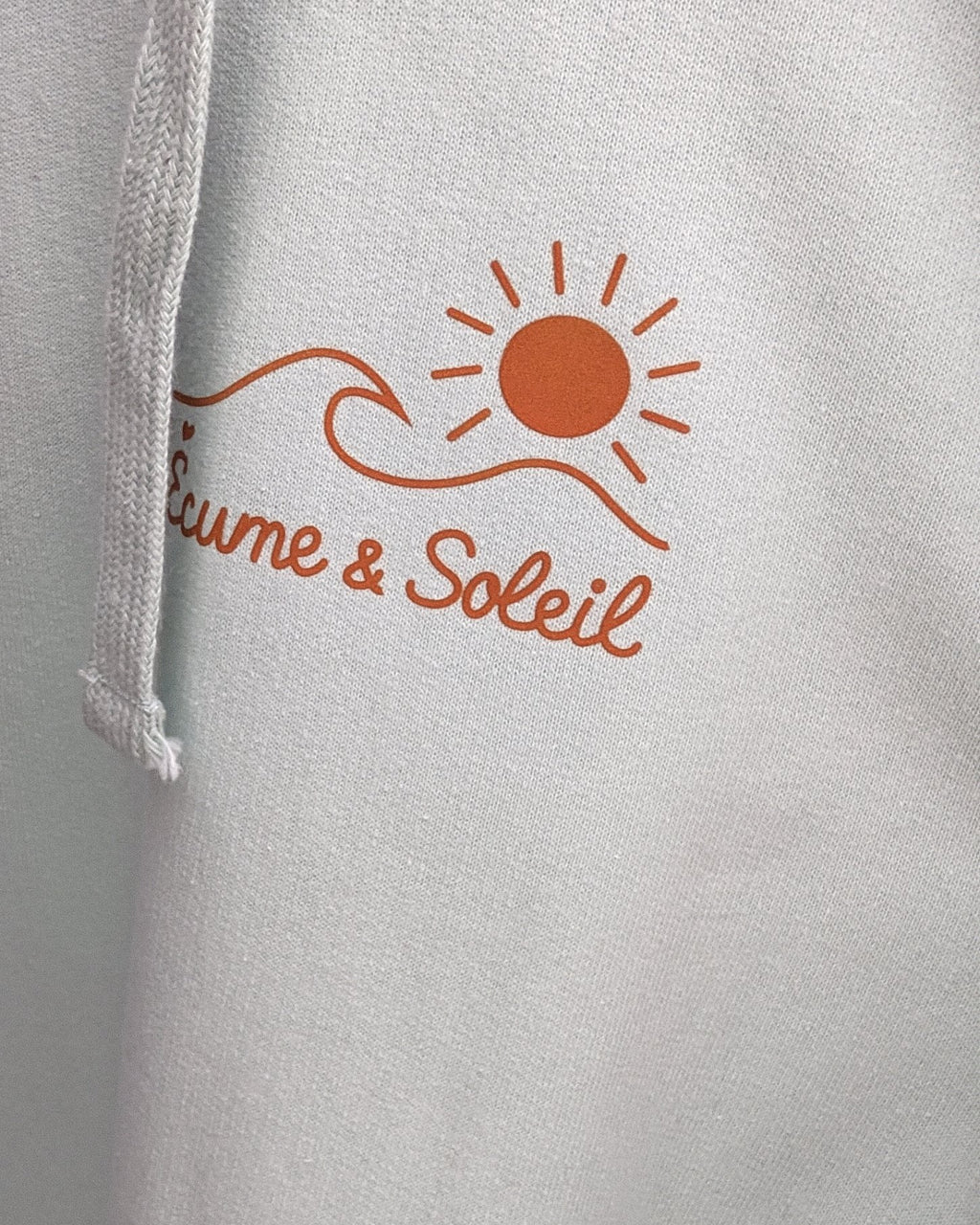 Sweat à capuche blush mint, logo soleil & vague et signature Écume & Soleil marqués au cœur