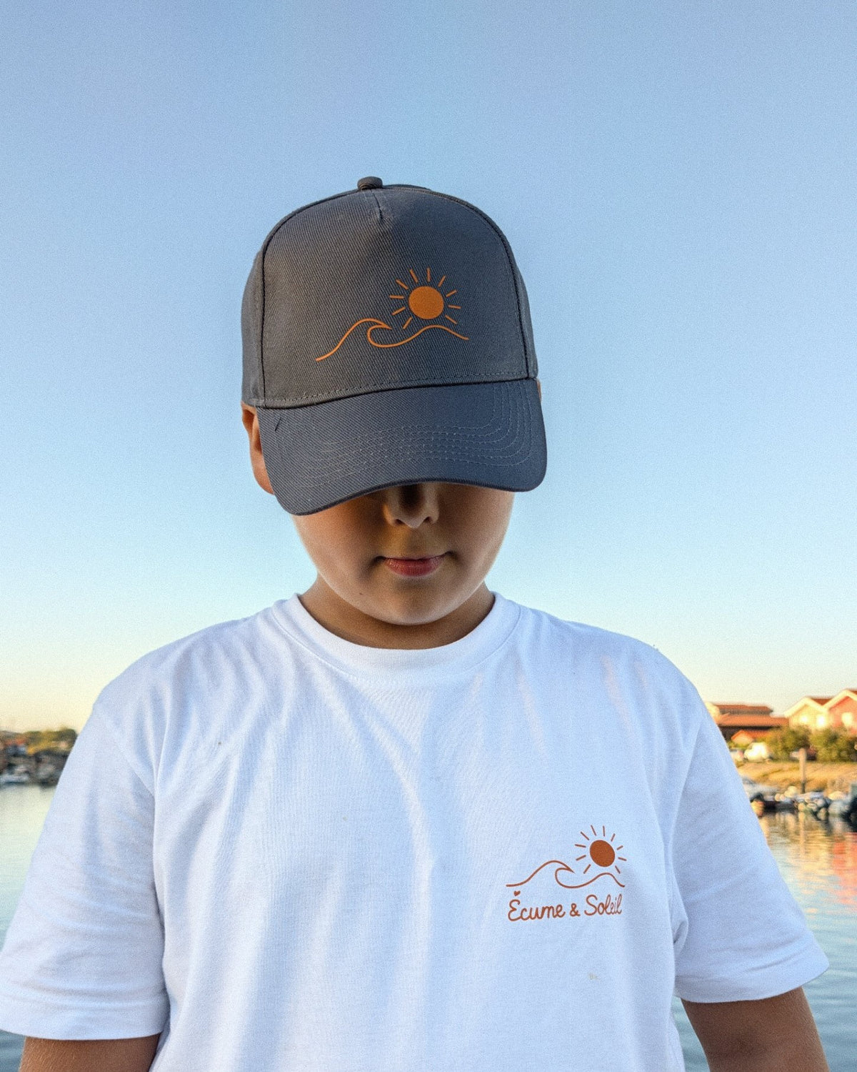 Casquette Écume & Soleil gris foncé vue de face, logo soleil et vague marqué en orange