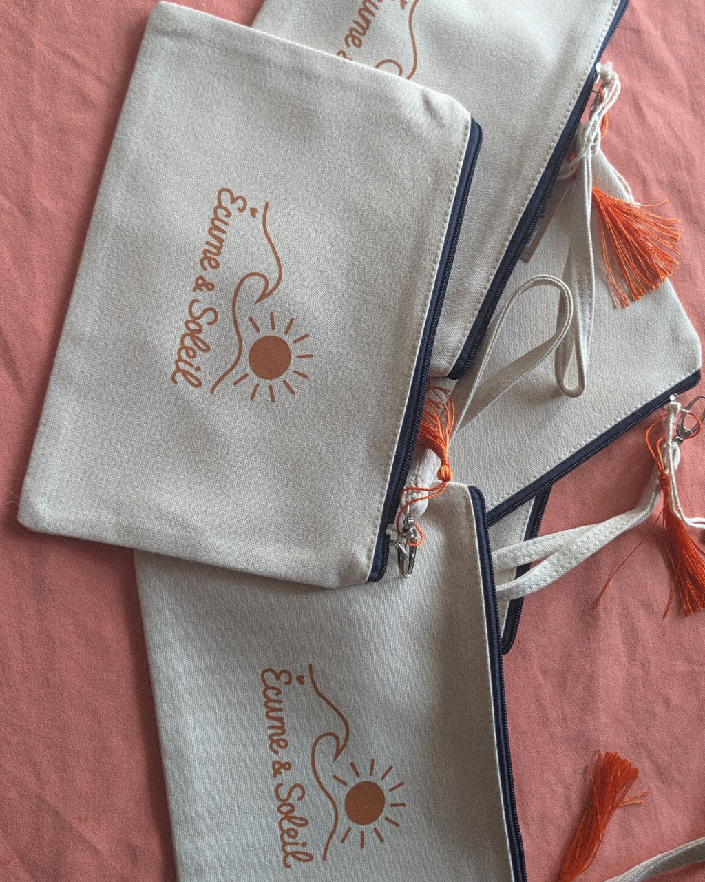 Pochettes Écume & Soleil écrues avec pompon orange, signature en terracotta