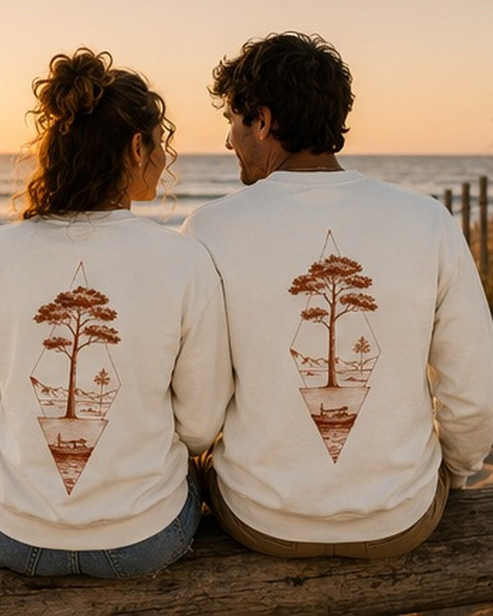 Pull Écume & Soleil motif Île & Pins beige, plié sur le sable