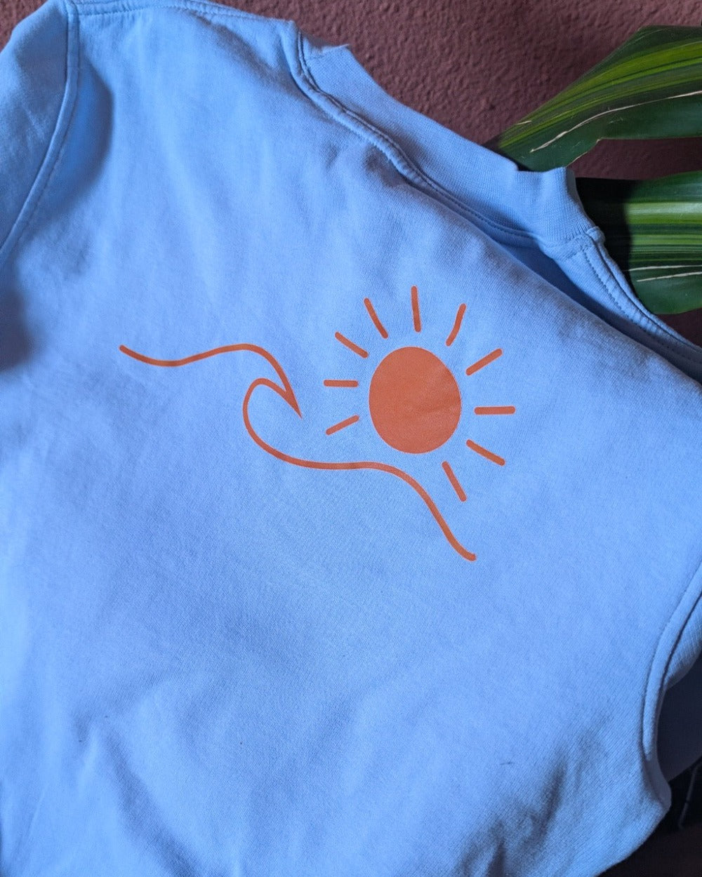 Pull Le Basique bleu ciel, détail du logo soleil & vague au dos