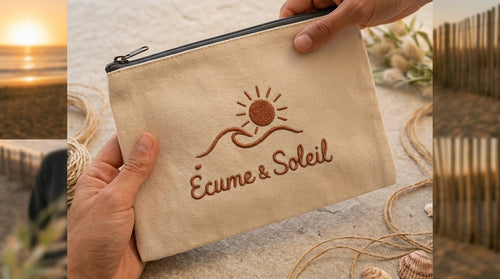 Pochette Libre Ensemble Écume & Soleil en coton sable tenue en main, logo soleil et vague