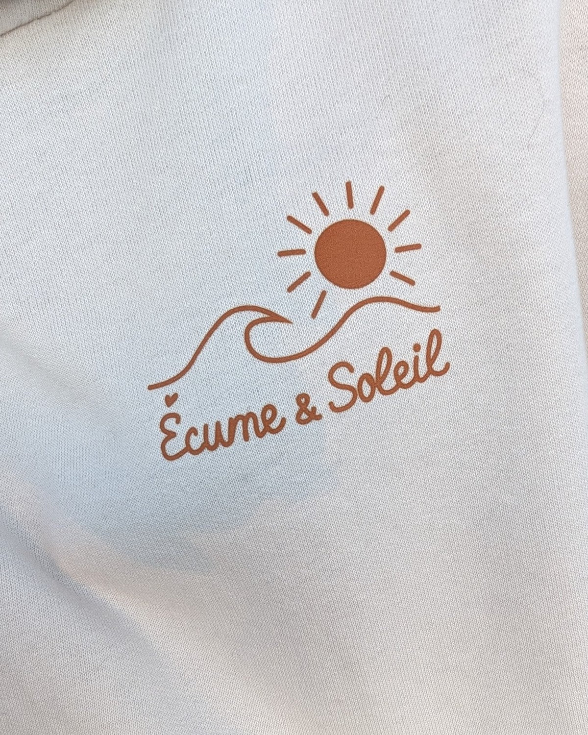 Sweat à capuche écru, logo Écume & Soleil soleil et vague marqué au cœur