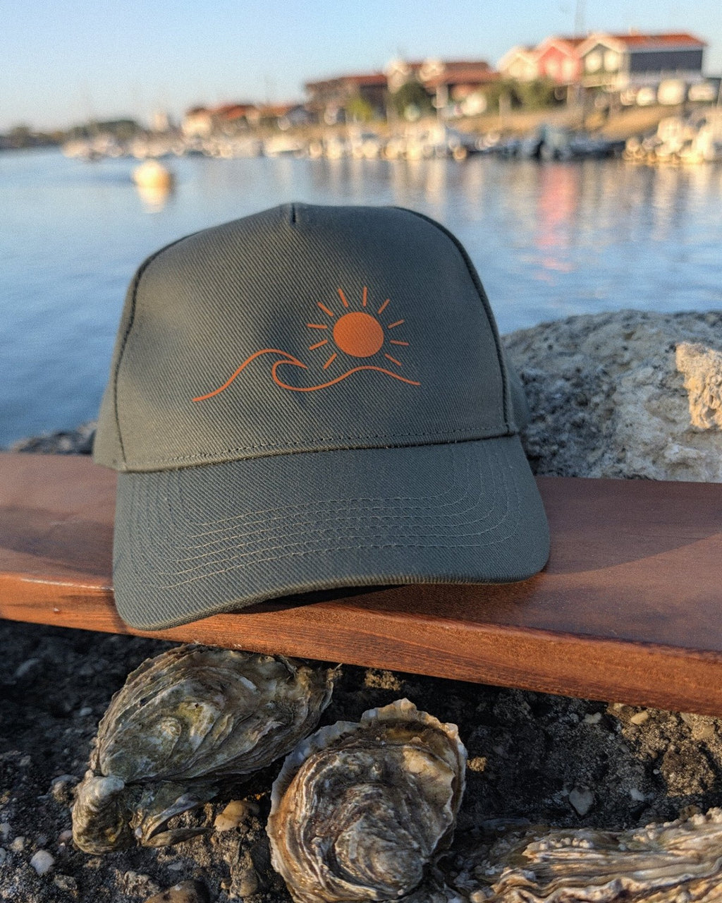 Casquette Écume & Soleil kaki posée sur une planche au port de Gujan