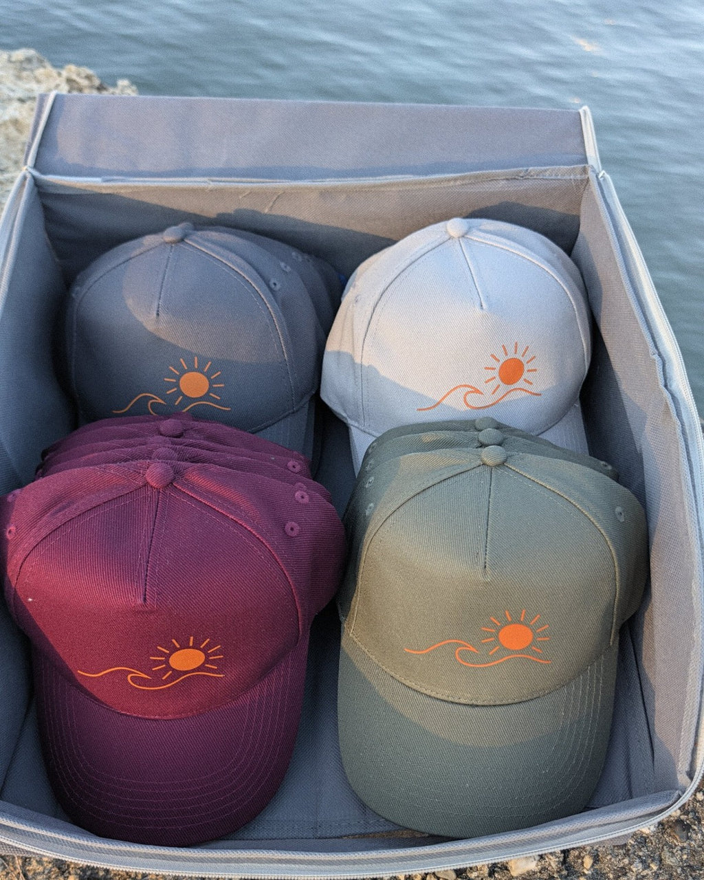 Les casquettes Écume & Soleil rangées dans leur boîte, quatre coloris