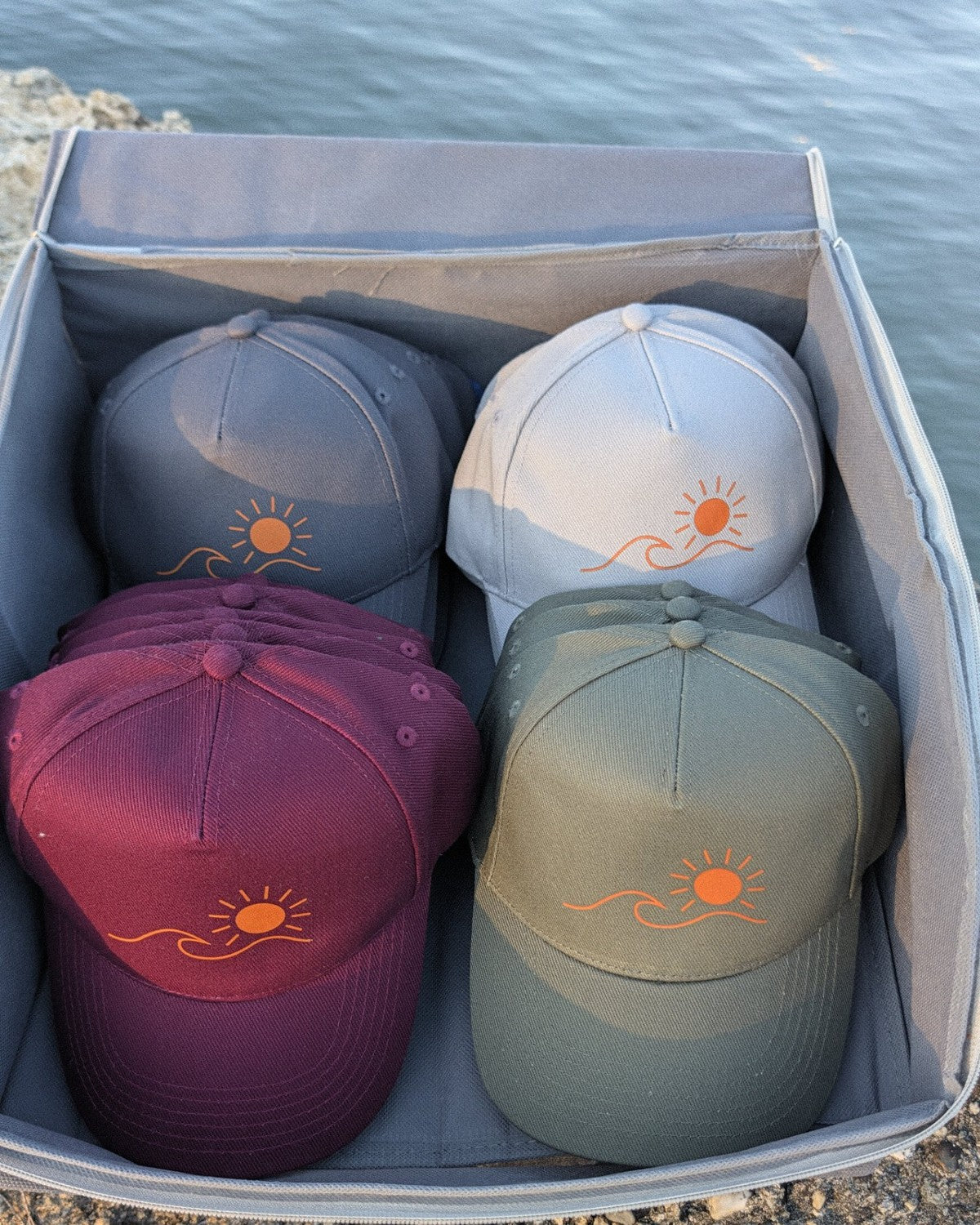 Les casquettes Écume & Soleil rangées dans leur boîte, quatre coloris