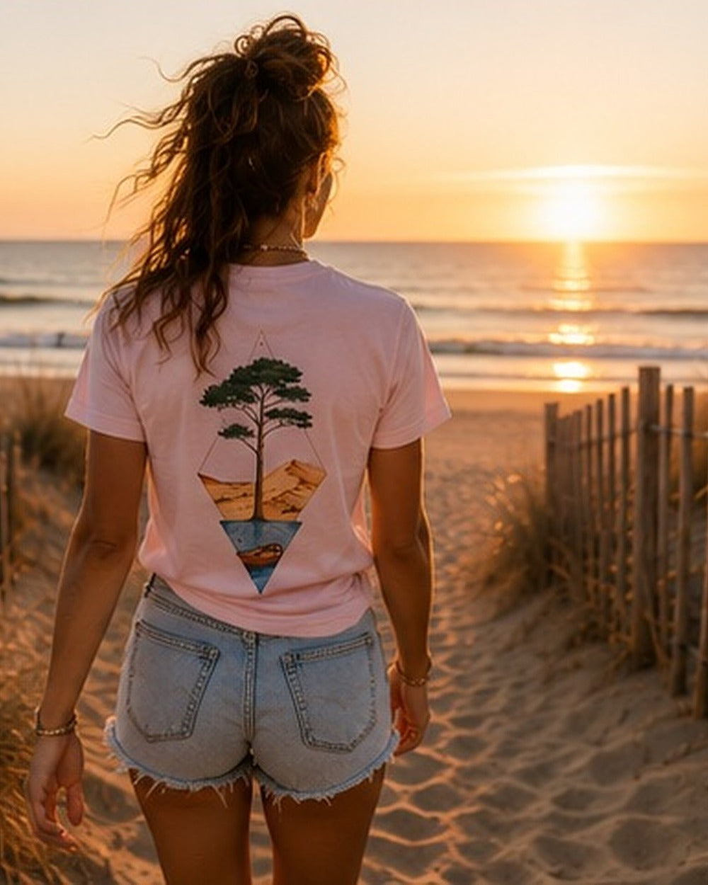 T-shirt Écume & Soleil motif Île & Pins Couleur rose, porté de dos face au coucher de soleil