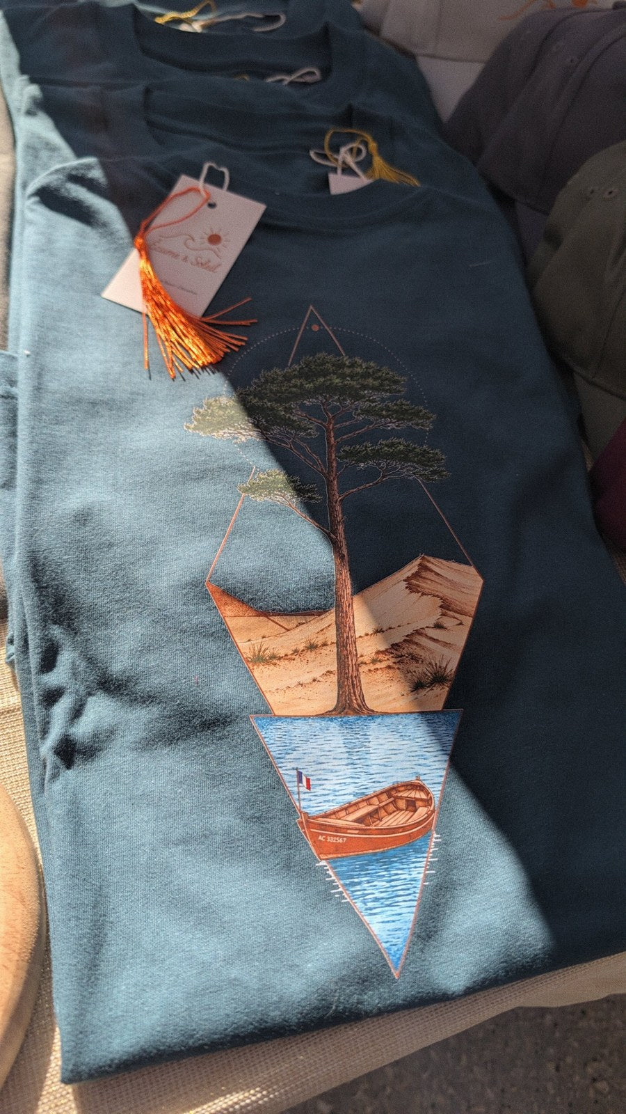 T-shirt Île & Pins Couleur bleu vert plié : pin, dune et pinasse en couleurs