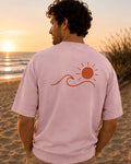 T-shirt Écume & Soleil motif Le Basique, coloris rose, porté de dos au coucher du soleil